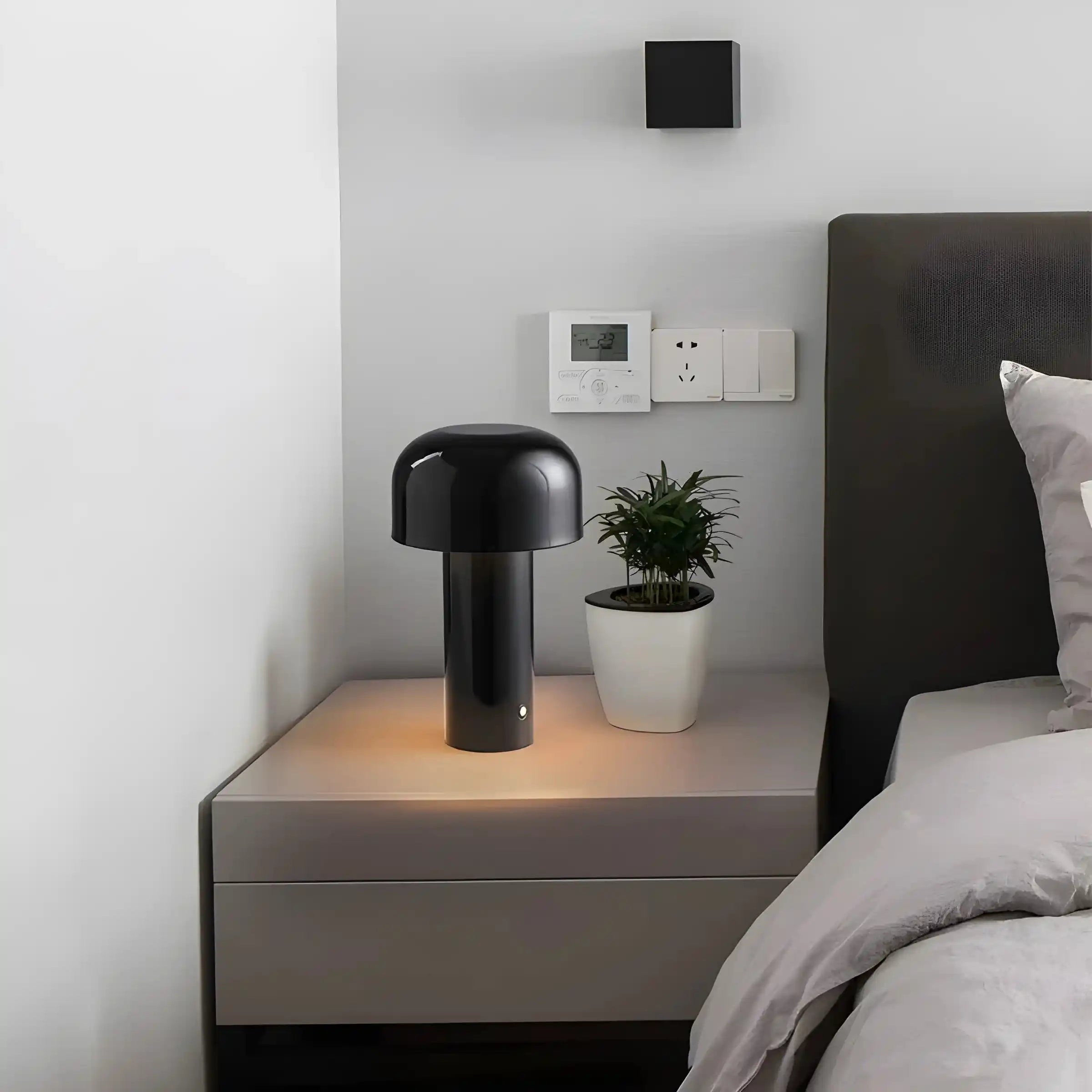 Modern black table lamp with a mushroom-shaped shade on a bedside table.