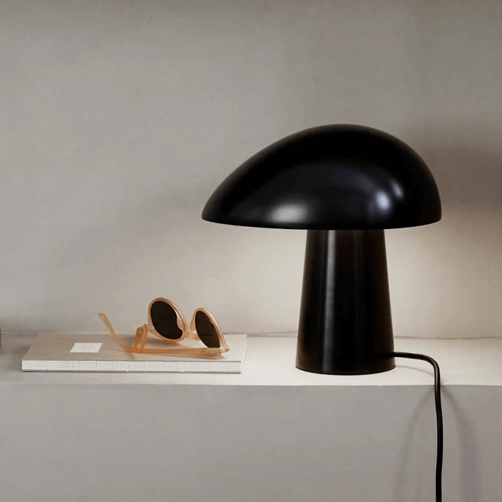 Black mushroom-shaped table lamp with a rounded dome top and cylindrical base.