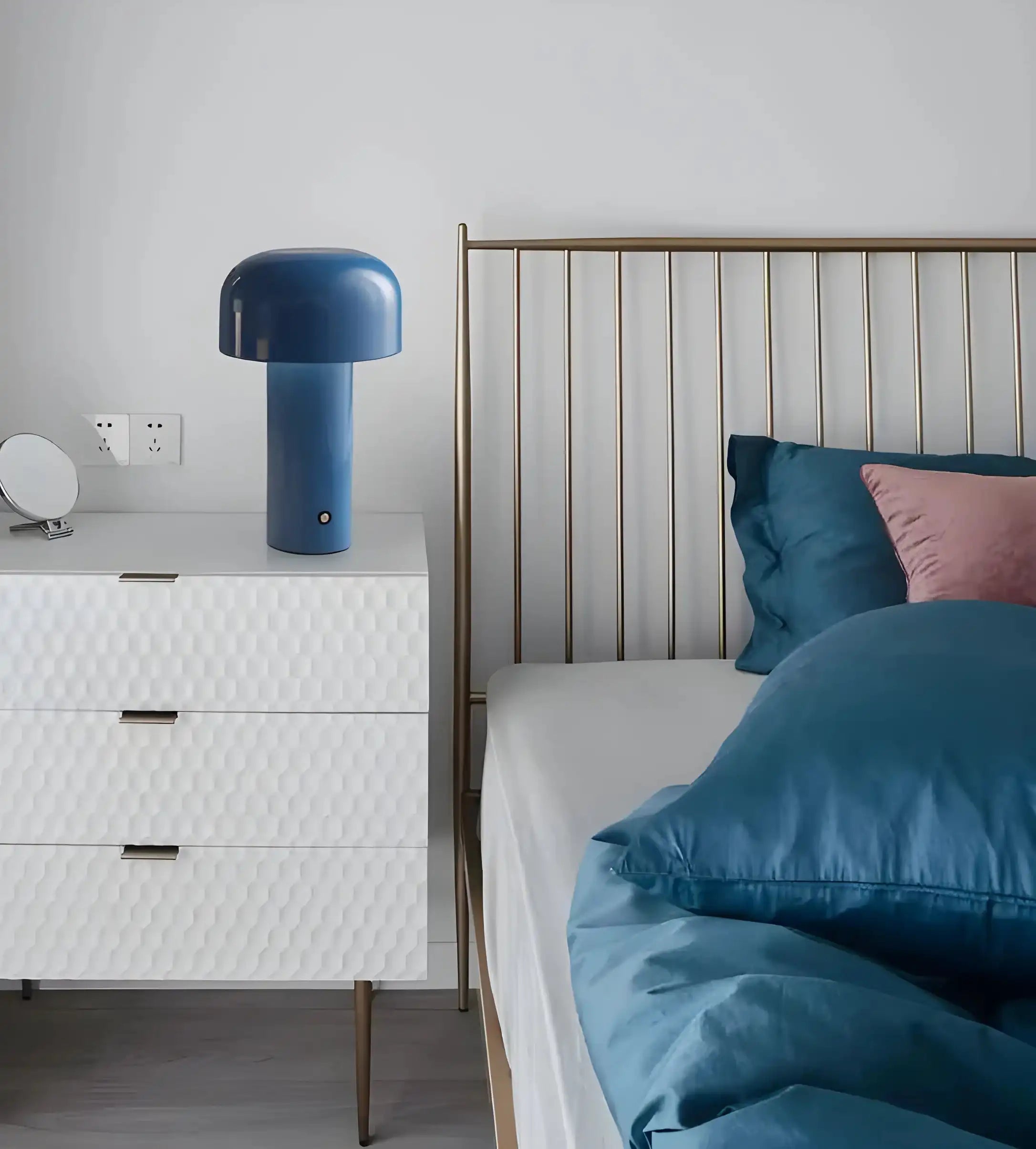 Blue mushroom-shaped table lamp on a white bedside drawer.