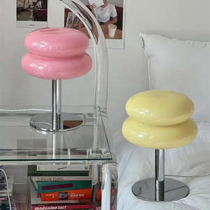 Colorful stool-shaped lamps with rounded, stacked cushion-like tops on metal bases.