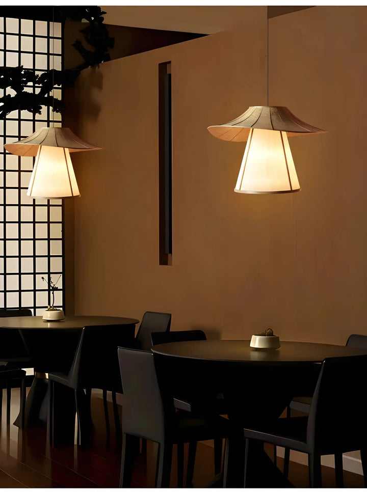 Illuminated pendant lamps with angular shades hanging above a dining table.