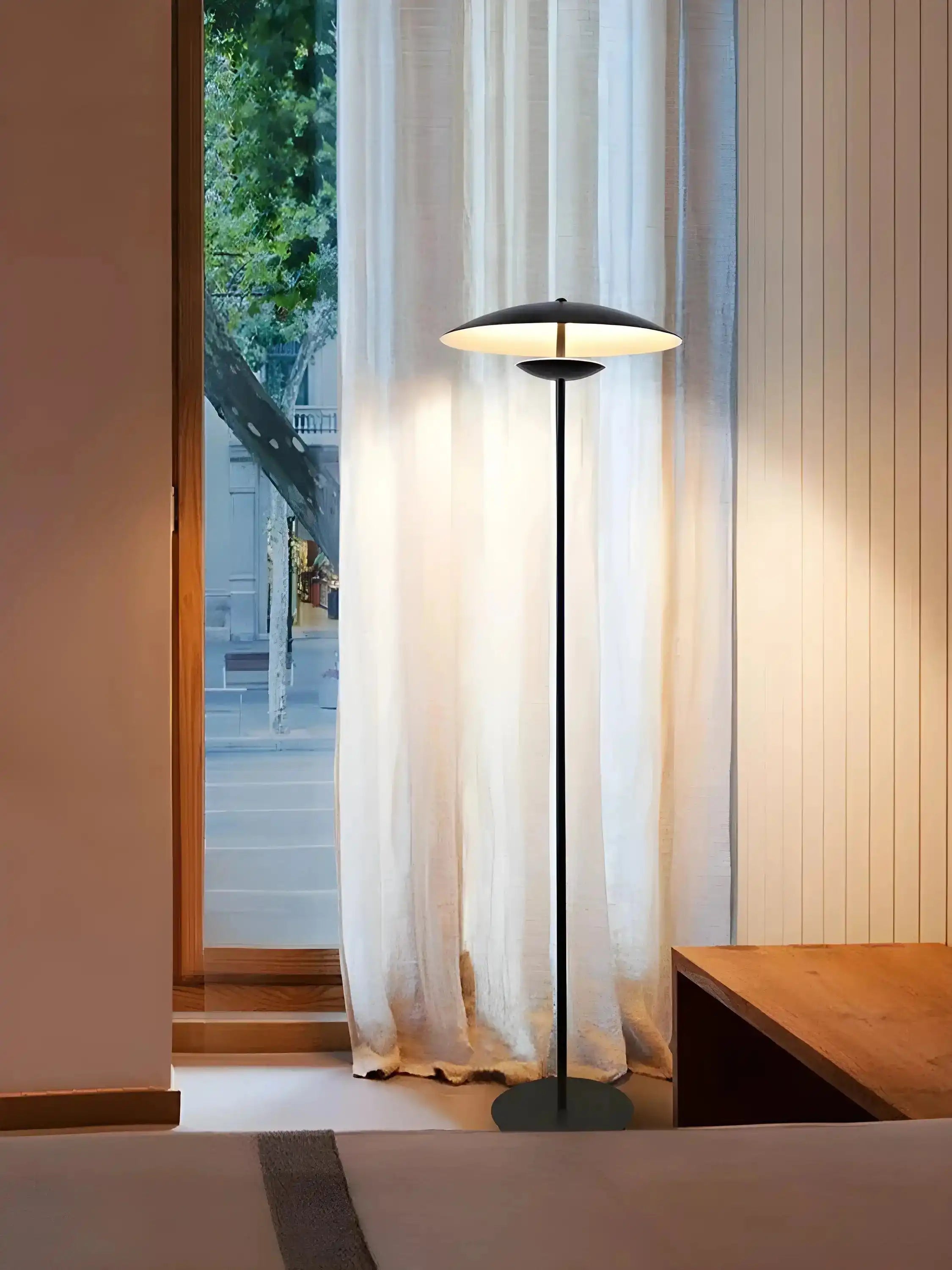 Modern floor lamp with a sleek black stand and a flat circular shade.