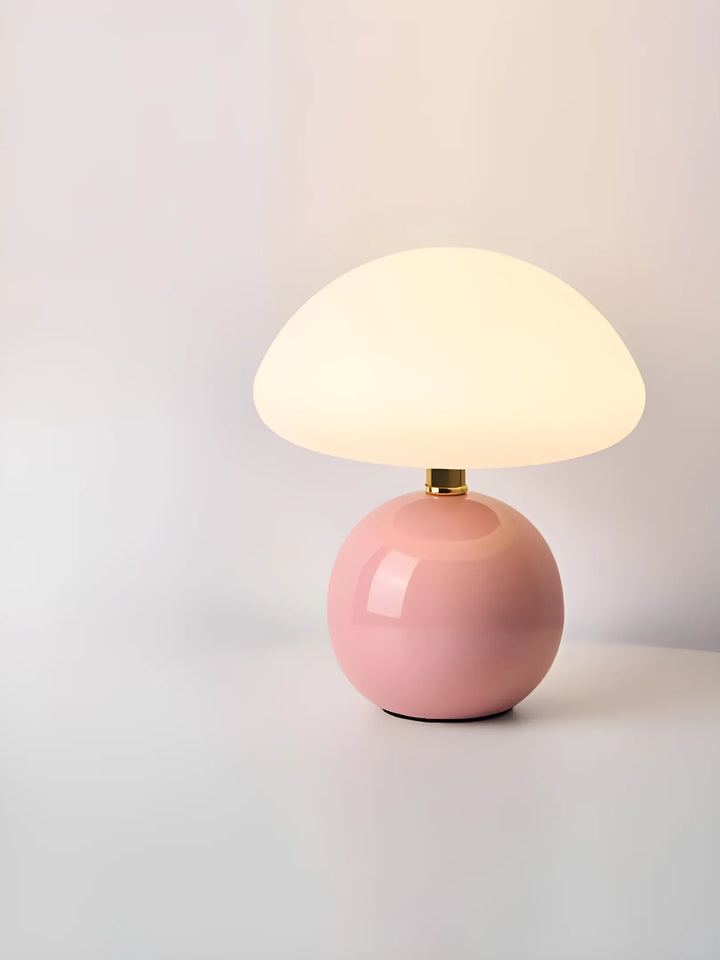 Pink ceramic table lamp with a round base and domed white shade.