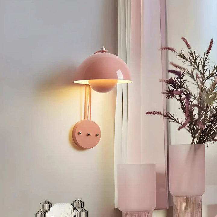 Pink dome-shaped wall sconce with a warm glowing light.