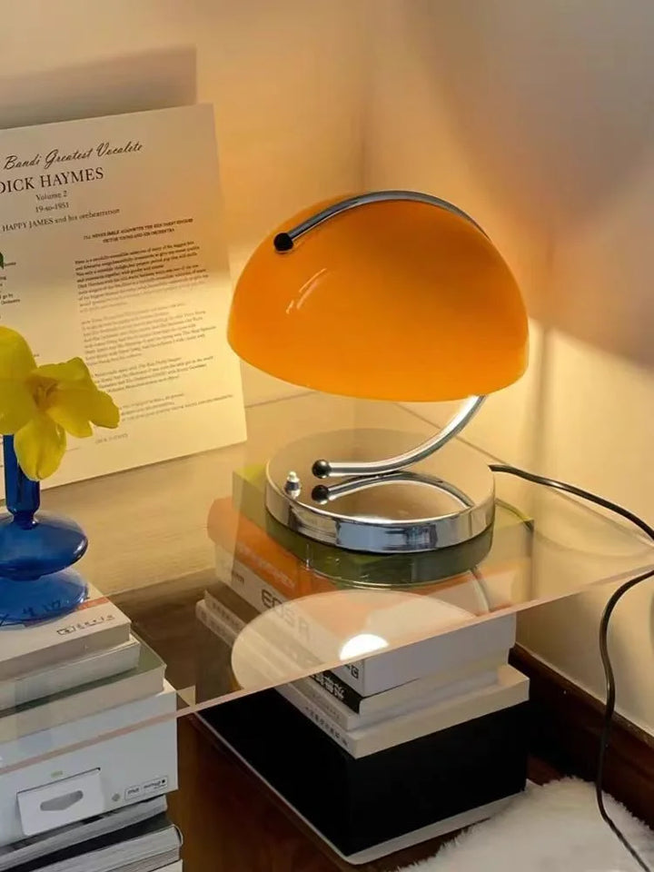 Retro-style desk lamp with an orange dome shade and curved chrome base.