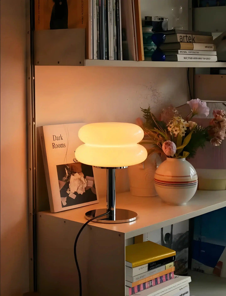 Glowing table lamp with a round, layered shade on a metal base.