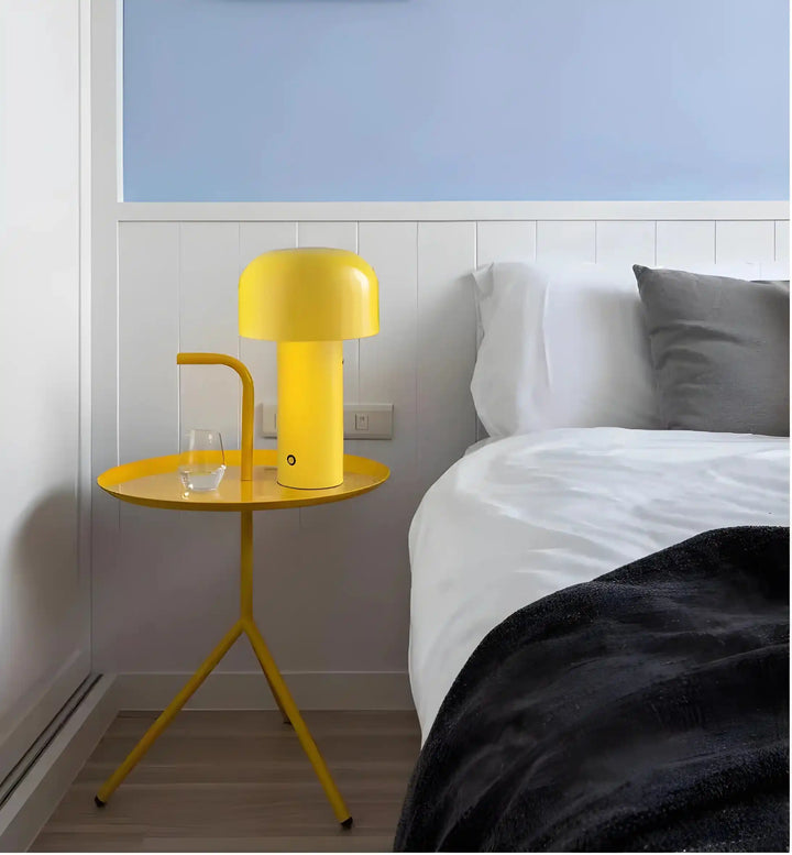 Yellow bedside table with a matching lamp and glass of water.